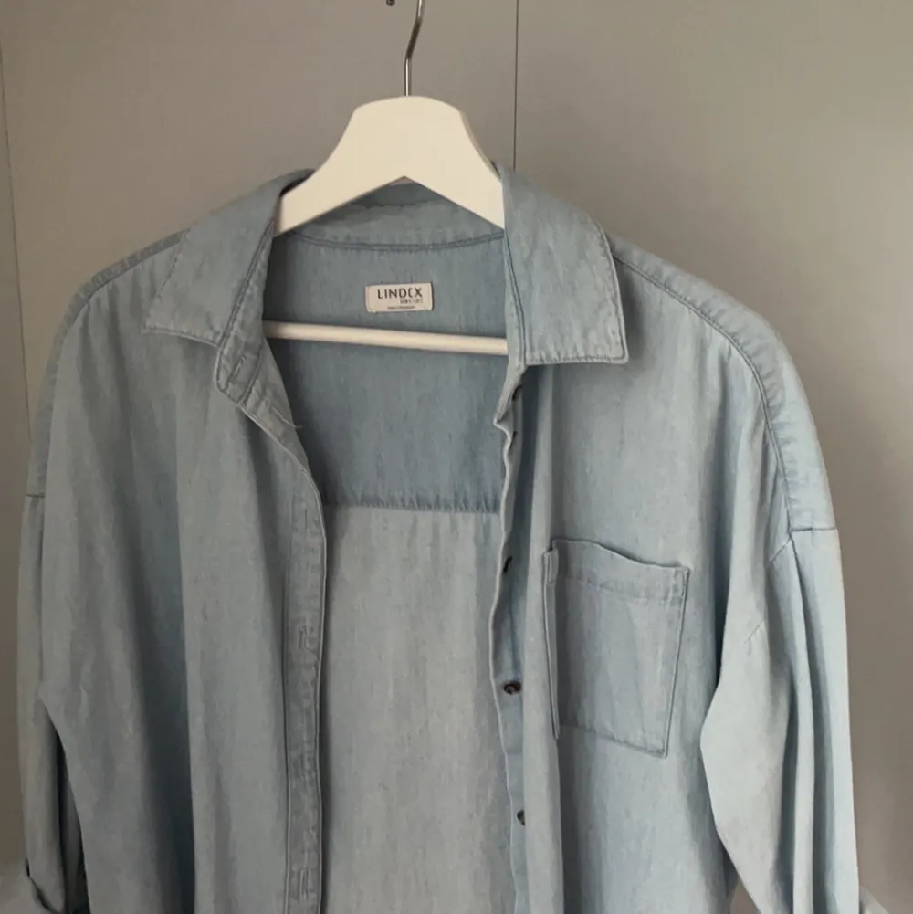 En ljusblå jeansskjorta från Lindex i bra skick, inga defekter. Passar mig som har storlek XS, är lite oversized på mig. Säljer pga att den inte kommit till användning. Jätte fin till en sommarklänning. Köparen står för frakt. . Skjortor.
