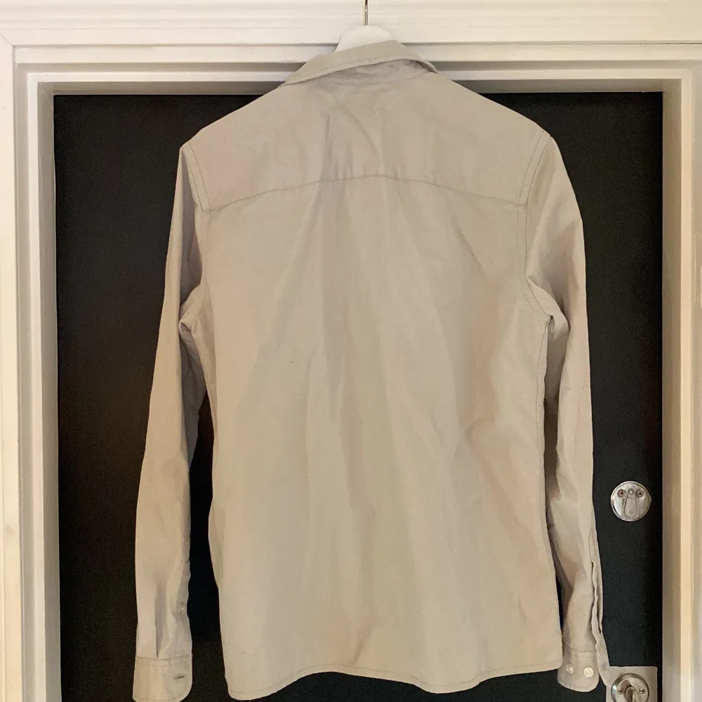 En ljusgrå jacka/overshirt i storlek M, har en liten fläck på ryggen annars fint skick!. Skjortor.