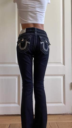 Äkta true religions jeans, väldigt mörk blåa med silvriga nästan vita sömmar.  Fickorna har silver och stenar på fickorna. Jag är 163 cm! Aldrig använda, köpt för 1800kr i london. 
