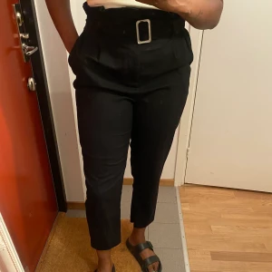 H&M Svarts  byxor storlek EU38 - H&M svart kostym byxor i bra skick. Botten av ett ben behöver sys ihop igen och den silvrige delen på beltet ska vara svart med tyg. Men annars är den perfekta. 