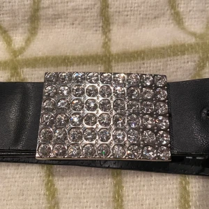 Skärp med Rhinestones  - Coolt skärp från märket Joy med rhinestones. Det är i relativt bra skick då alla rhinestones sitter på men själva skärpet är lite vågigt efter det har varit använt. Kan skicka fler bilder om det önskas.