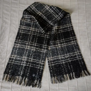 Svart/grå/beige/vit rutig halsduk med fransar, Made in France - Sjukt snygg svart/grå/beige/vit rutig lite lurvig halsduk med fransar. Made in France. Ca 150 cm lång exkl. fransarna och 30 cm bred. 73% Akryl 14% polyester 13% ull. Bara använd någon enstaka gång. 