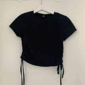 Kroppad T-shirt med snöre - Säljer nu denna T-shirt med snörning från Shein då den inte passar mig längre. Köparen står för frakten. Betalning sker via swish. Kan skickas med spårbar frakt