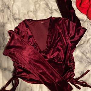 En vinröd v-ringad tröja med dragsko på båda sidorna (under armarna typ). Stl M men passar S
