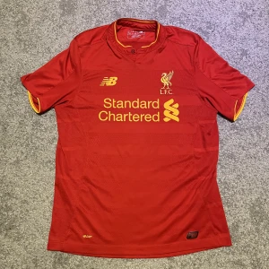 Liverpool Fotbollströja - Liverpool fotbollströja 2016-2017. Tröjan är använd och Liverpool, New Balance märket och sponsorn är lite skadat. Jag säljer den pga att jag inte har någon användning för den och för att den är för stor. Pris kan diskuteras.