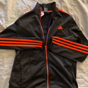 Adidas träningströja  - Nu säljer jag denna svart/orangea tränings jackan/tröjan från adidas, storlek 13-14år (skulle även säga att det passar Xs/S) den är nyskick men köpt för ganska länge sen. Jag säljer den för 30kr + 49kr frakt! Hör gärna av er vid intresse eller frågor!💕