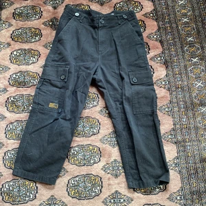 Zara byxor M -  Svarta byxor med många fickor, ska vara lite korta nedtill och är lite slitna men väldigt snygga. Man kan säga att det slitna på byxorna gör de lite extra snygga. Byxorna har använts mycket.  