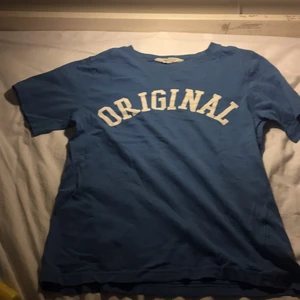 Blå med vit text T-shirt - Den är  storlek 134/140 men är stor som 146/152 m.m den är nästan nyköpt men ville käna lite pengar så jag säljer denna för lågt pris. Den är från HM men köpt i backa plan i Göteborg 