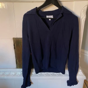 Tröja &otherstories - Stickad tröja från &otherstories i 100% ull, sparsamt använd och nästan i nyskick! Varm och skön tröja med tenniskrage och fina volangdetaljer i slutet av armarna!