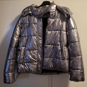 Zara jacka - Silverfärgad jacka från Zara i strl M. Avtagbar huva med dragkedja. Sparsamt använd.