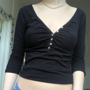 Svart tröja - Svart tröja med knappar, så man kan justera hur djup ringning man vill ha. Ger fin klyfta!