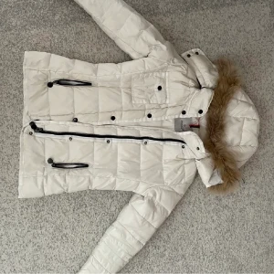 Vit Moncler Jacka - Lägger ut igen, ngn klicka på köp nu.  Säljer min fina moncler jacka. Jackan är i väldigt bra skick dock med ett hål vid ärmhålan (se bild 3) men det ska inte vara något stort besvär. Jackan är äkta (qr kod samt serielapp). För fler bilder skriv. 