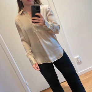 ARKET guldig blus - Oversized, guldig blus från Arket med skjortkrage och längre bakstycke. Storlek 36/165cm. Endast använd 2-3 gånger. Nypris 500kr.