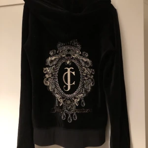 Juicy Couture tröja - Tjocktröja/huvtröja i ”sammetsmaterial” från Juicy Couture. Stl XS. Svart med stor bling logo på ryggen. Använd enstaka gånger, i fint skick! 