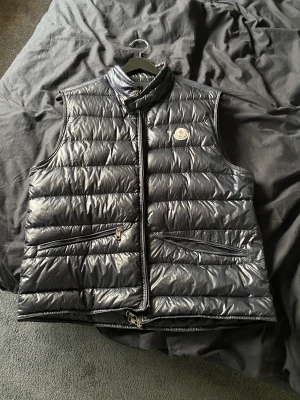 Moncler gui väst - Säljer nu min mörkbåa moncler väst,självklart äkta Skick:7-10 Storlek:2(passar runt 170cm) Dragkedjan är sönder och även ena dragkedjan till fickan. 