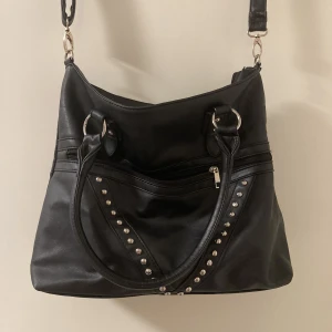 Handväska - En snålt använd handväska i fuskläder med många fack. Väskan delas upp i två delar inuti av ett fack varav sömmen lossnat lite från kanten men inget som stör funktion 