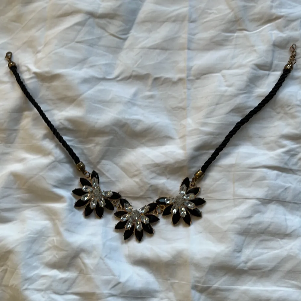 Ett svart halsband med blommor. . Accessoarer.