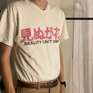 Vaporwave T-shirt - Cool vit t-shirt från UO med texten ”Reality can’t compete” kan inte garantera att det är samma som står i Rosa då jag inte vet vilket språk det är men jag antar att det är en översättning :)
