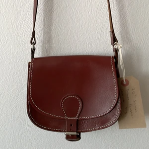 Axelremsväska - Liten axelremsväska köpt secondhand i Brighton. Gjord i läder, varm brun färg och silverdetaljer. 