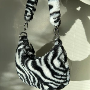 urban outfitters faux fur zebra väska - Superfin väska i zebramönster från urban outfitters!! Använder tyvärr inte längre så har beslutat mig för att sälja den. Den är i superfint skick och bara använd ett fåtal gånger🖤🤍🖤🤍 Skriv om du är intresserad eller har frågor o funderingar❣️