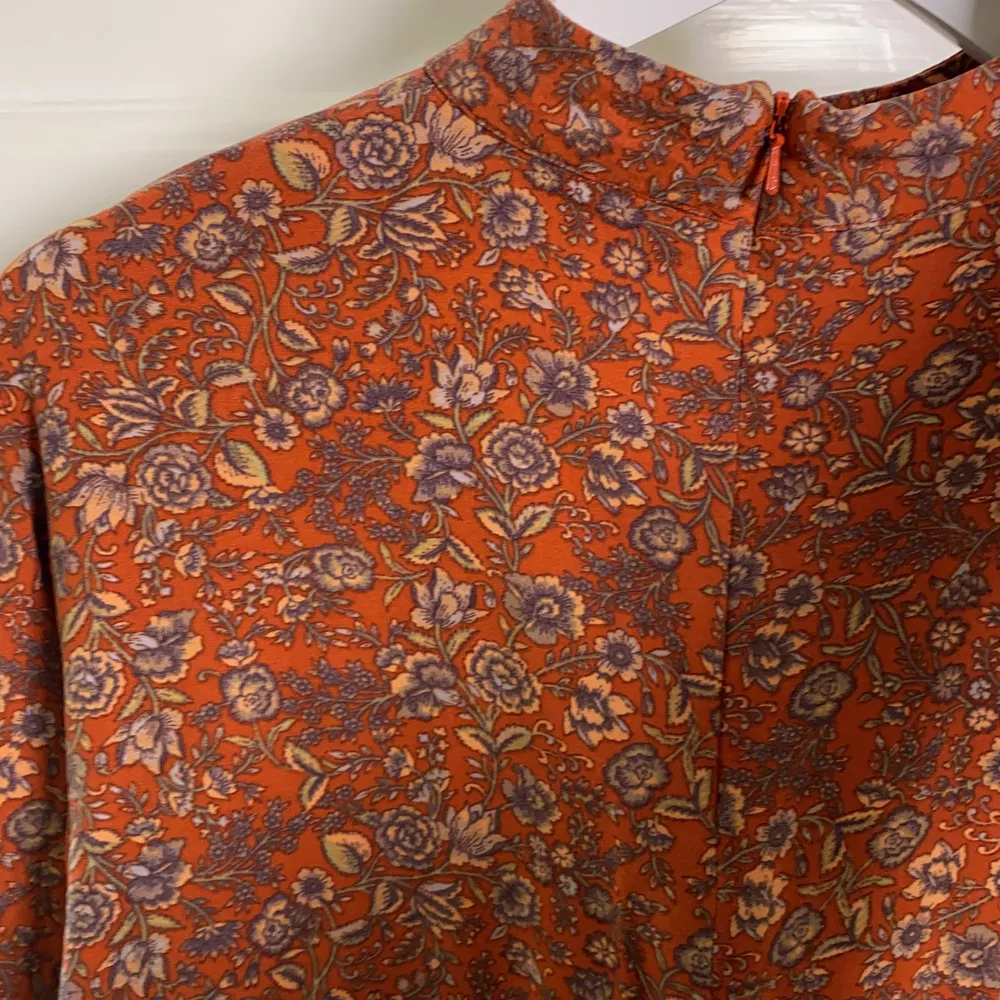 Rostbrun tröja med blommor från Indiska. Dragkedja i ryggen. Liten krage, nästan som en polotröja. Använd ca 5 ggr. . Toppar.