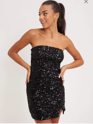 Glittrig bandeau klänning - Nelly  - Säljer denna super fina klänning som tyvärr bara kom till användning för mig på nyår! Den är iprincip oanvänd! Nypris på denna var 399kr