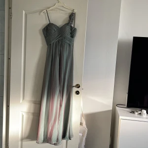Aftonklänning  - Grön aftonklänning. Knäppning med dragkedja och knappar baktil. 