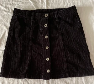 Manchester kjol - Svart manchester kjol med metall knappar.St 158