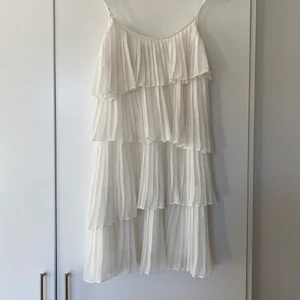 Vit volangklänning 34 - Vit plisserad volangklänning frpn Zoul storlek 34. Passar även 36/S då axelbanden går att justera.