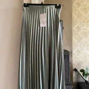 Fin lång turkos kjol från Zara i glansigt silkesmaterial. Helt oanvänd!