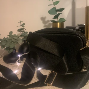 Svart axelväska  - En lätt ficka där inne (bild 2) och en på utsidan.👜