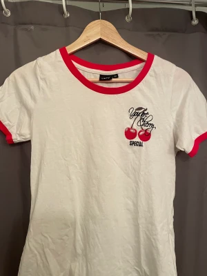 vit t-shirt med körsbär motiv  - lite vintage-ish 50s likande t-shirt med ett cherry motiv. Det är i barn storlek men passar som en s/xs (jag är 175 och den passar mig🥰) Säljer för att jag knappt använder den längre😔Köpte den för 199kr men säljer för 85kr 