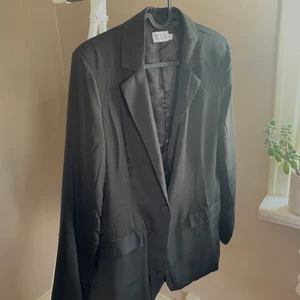 Svart kavaj från XLE - Svart kavaj från XLE i storlek M. Inte så tung i materialet så är väldigt skön att ha på sig. Skick utan anmärkningar. SKICKAS med postnords fraktpåse för 63kr, önskas spårbart tillkommer det.