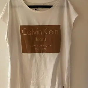 Vit Calvin Klein T-shirt med tryck i brunt. Oversized modell