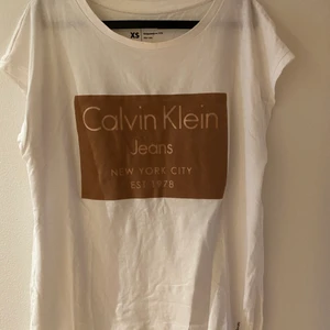 Calvin Klein T-shirt  - Vit Calvin Klein T-shirt med tryck i brunt. Oversized modell