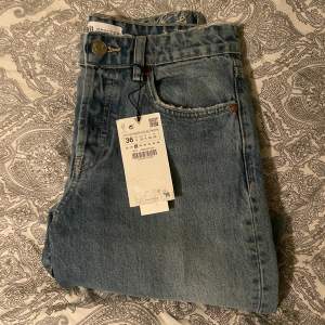 Ett par blåa jeans i storleken 36, med styv tyg, och  en medelhög midja. Knäppning fram med metallknappar.  Original pris 350kr Är helt nya och har inte använts. 