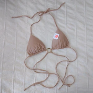 Oanvänd beige bikinitopp - IW Saint-Tropez top  - Oanvänd bikiniöverdel i en väldigt fin beige/beigerosa lite skimrig färg. Modellen heter Saint-Tropez (IW Saint-Tropez top). Kna skickas med 2 frimärken (30 kr). Köptes för 179 kr. 