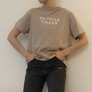 T-shirt - Beige T-shirt i stl S med hög krage och vaderade axlar.