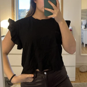 Svart Tshirt från zara - Fin Tshirt från zara med volanger på armarna.