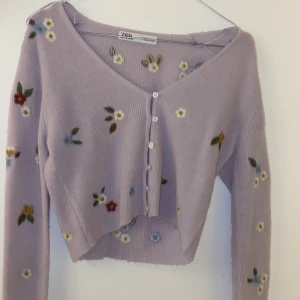 Croppad kofta - Stickad lila kofta med blommor från zara. Ganska kort i längden, typ croppad