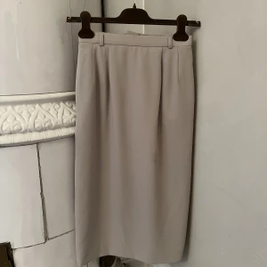 Pennkjol beige - Superfin pennkjol från Tokyo. Klassisk style, tight upptill. Strl 34. Går mig till precis under knäna, jag är 158cm lång. Okej skick.