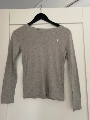 Ralph Lauren grå långärmad  - Säljer min Ralph Lauren långärmad, aldrig använd. Köpt från Kidsbrandstore. Säljer för den är tyvärr för liten och inte min stil längre. Skriv för flera bilder. 