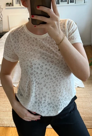 Vit T-shirt i leopardmönster - Vit t shirt från Scotch & Soda. T-shirten har ett leopardmöster som är lätt genomskinligt