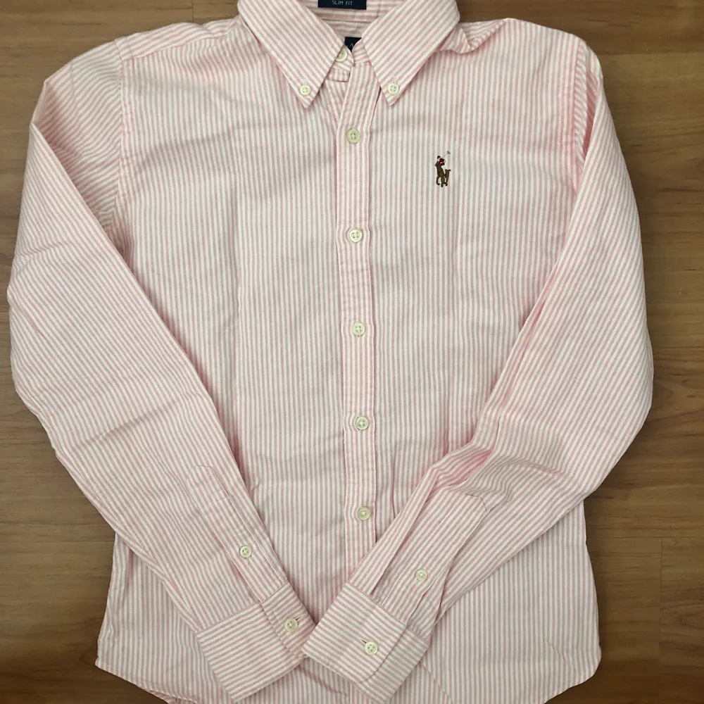 Säljer den här fina Ralph Lauren skjortan som är i nyskick. Den är rosa/vitrandig och är i storlek 0 (slim fit) vilket motsvarar XS. . Skjortor.