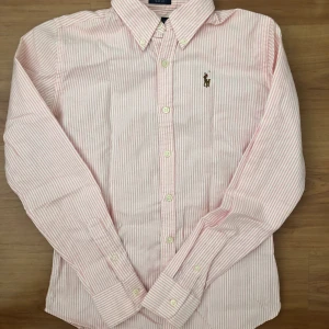 Ralph Lauren skjorta  - Säljer den här fina Ralph Lauren skjortan som är i nyskick. Den är rosa/vitrandig och är i storlek 0 (slim fit) vilket motsvarar XS. 