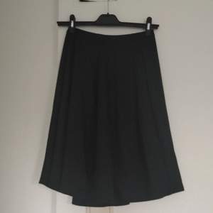 Halvlång svart kjol. Mjukt material dragkedja i rygg, vidform. Storlek small