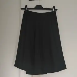 Halvlång svart kjol. Mjukt material dragkedja i rygg, vidform. Storlek small