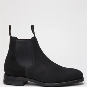 Svarta Loake Chelsea boots i mocka/suede - Fina högkvalitativa Chelsea boots från märket Loake. Modellen heter 1880 Classic Chatsworth Chelsea Boot och är i suede/mocka. Randsydd konstruktion. Tillverkad i England. Innersula i läder. Yttersula är Goodyear Welted