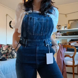 Hängselbyxor i jeans  - Fina hängselbyxor från other stories! Högmidjade. Köpta för länge sedan men är helt oanvända. Skulle skicka tillbaka de för en annan storlek men hann inte. Lappen är kvar, har aldrig använt de. Köpta för 850