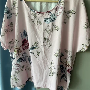 Blus  - Aldrig använd. Söt blus med dragkedjor i sidan. Kort, vid modell. Ljus rosa med blommönster. 